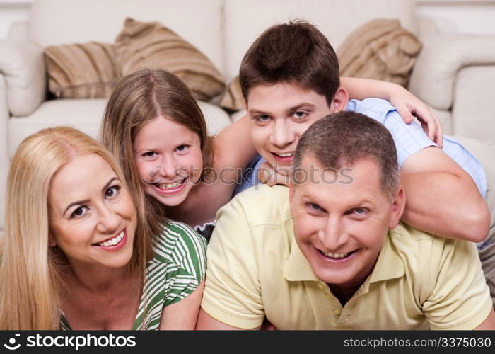 Smiling family lying together on the floor in living room