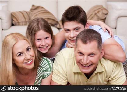 Smiling family lying together on the floor in living room