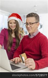 Smiling father and daughter shopping online at home during Christmas