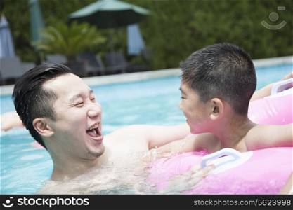 Smiling father and son playing in the pool