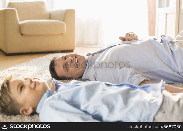 Smiling father and son relaxing on floor at home