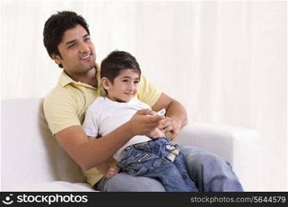 Smiling father and son watching television