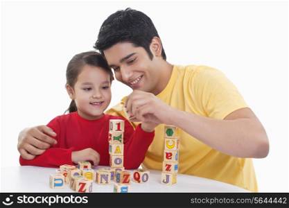 Smiling father assisting girl in playing block game