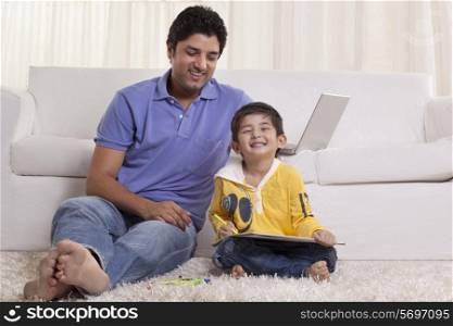 Smiling father assisting his son in drawing at home