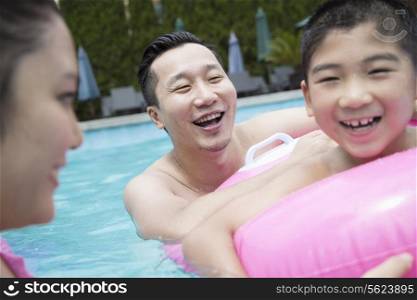 Smiling father, mother, and son playing in the pool
