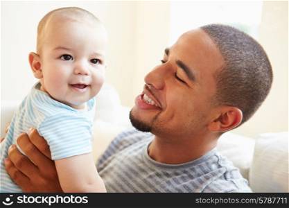 Smiling Father Playing With Baby Son At Home