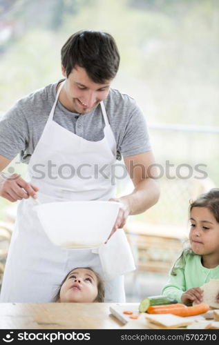 Smiling father preparing sandwich with daughters at home