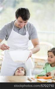 Smiling father preparing sandwich with daughters at home