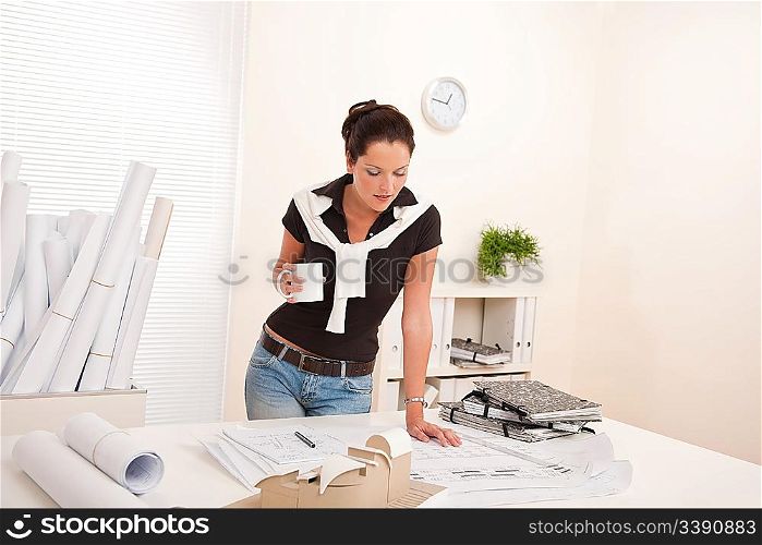 Smiling female architect at the office holding coffee