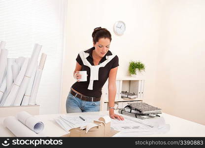 Smiling female architect at the office holding coffee