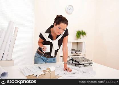 Smiling female architect at the office holding coffee