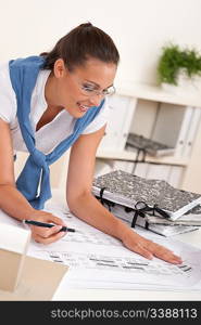 Smiling female architect watching plans at the office