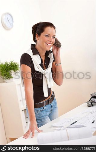 Smiling female architect with telephone at the office