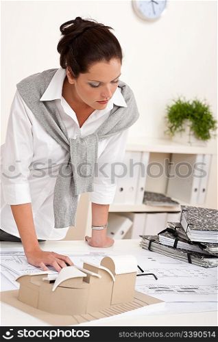 Smiling female architect working with plans at the office
