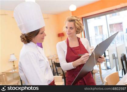 smiling female chef cook or baker with blank black menu