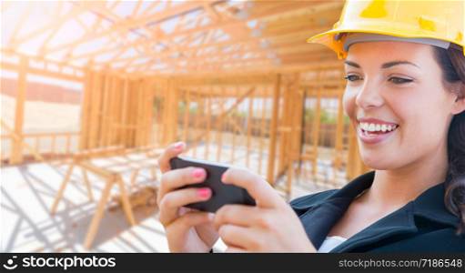 Smiling Female Contractor In Hard Hat Using Smart Phone At Construction Site.