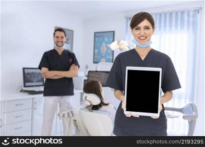 smiling female dentist showing digital tablet clinic