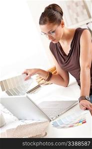 Smiling female designer with color swatch and laptop at office