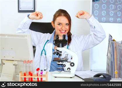 Smiling female doctor sitting in laboratory and rejoicing success&#xA;