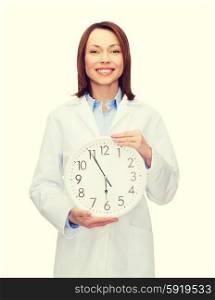 smiling female doctor with wall clock. healthcare and medicine concept - smiling female doctor with wall clock