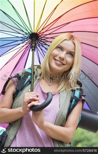Smiling female hiker holding umbrella