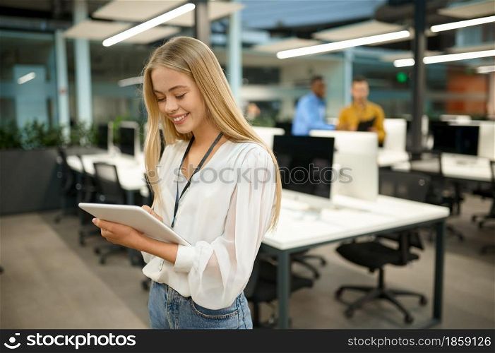Smiling female manager holds laptop, IT office interior on background. Professional worker, planning or brainstorming. Successful employee in modern company. Smiling female manager holds laptop, IT office