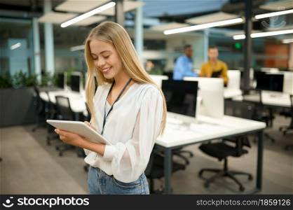 Smiling female manager holds laptop, IT office interior on background. Professional worker, planning or brainstorming. Successful employee in modern company. Smiling female manager holds laptop, IT office
