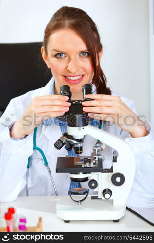 Smiling female medical doctor using microscope &#xA;