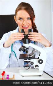 Smiling female medical doctor using microscope &#xA;