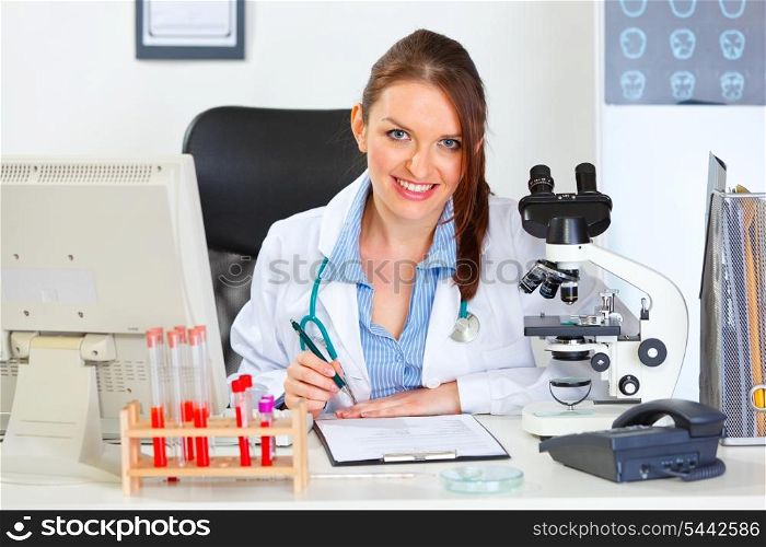 Smiling female medical doctor working with documents at office&#xA;