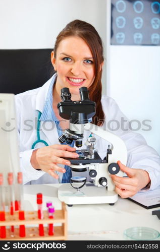 Smiling female medical doctor working with microscope in laboratory&#xA;