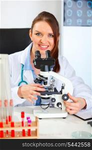 Smiling female medical doctor working with microscope in laboratory&#xA;