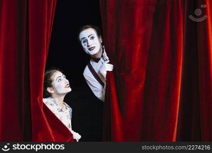 smiling female mime artist looking male mime artist peeking from curtain. Resolution and high quality beautiful photo. smiling female mime artist looking male mime artist peeking from curtain. High quality beautiful photo concept