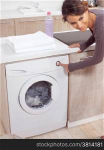 smiling female pressing a button on her washing machine