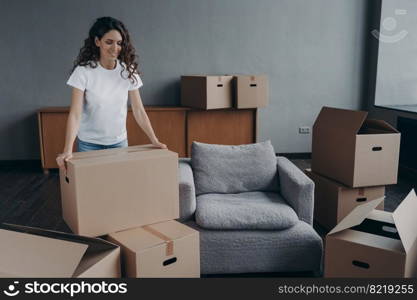 Smiling female tenant with cardboard boxes gathering things for relocation. Pleased hispanic woman renter packing belongings, preparing to move in first new home. Moving, mortgage concept.. Smiling female tenant with boxes packs things for relocation. Moving, mortgage, first new home