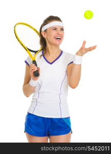 Smiling female tennis player throwing ball up