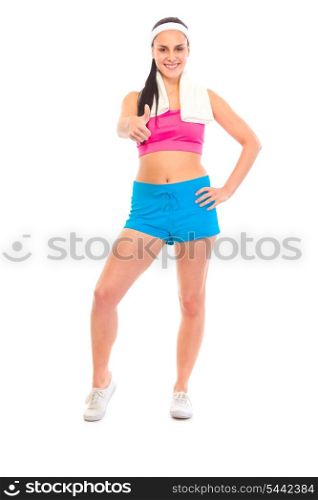 Smiling fitness girl with towel around neck showing thumbs up gesture isolated on white&#xA;