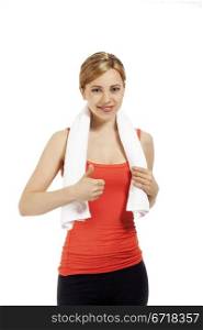 smiling fitness woman showing thumb up. young smiling fitness woman with a white towel showing thumb up on white background