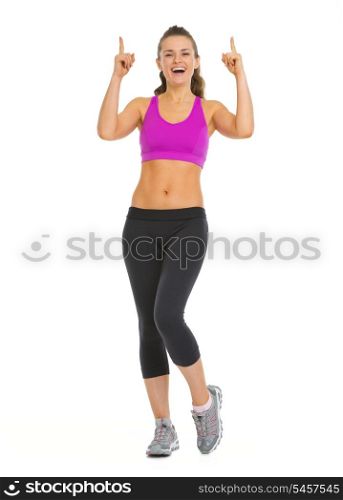 Smiling fitness young woman pointing up on copy space