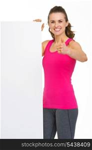 Smiling fitness young woman showing blank billboard and thumbs up