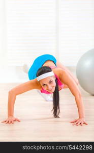 Smiling flexible young girl doing gymnastics exercise at living room&#xA;