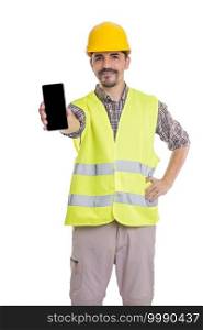 Smiling foreman in helmet and vest standing with hand on waist on white background and showing mobile phone at camera. Builder showing smartphone at camera