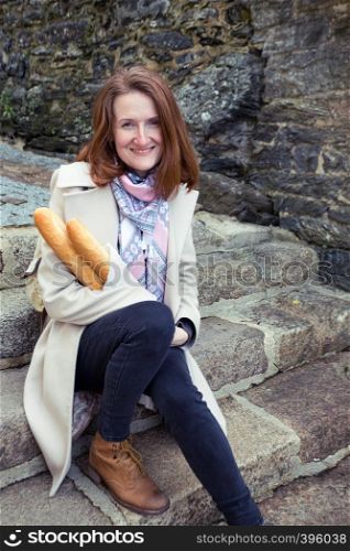 smiling French girl with baguettes on the street side of the city