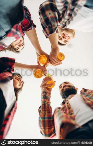 Smiling friends clink bottles with beer, bottom view, home party. Good friendship, group of people leisures together. Cheerful company celebrate the event