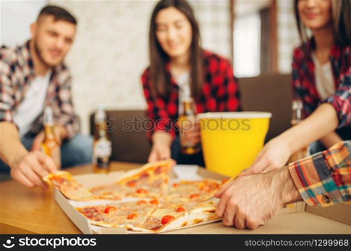 Smiling friends drinks beer with pizza at the house party. Good friendship, group of people leisures together. Cheerful company having fun. Friends drinks beer with pizza at the house party