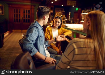 Smiling friends leisures at the counter in bar. Group of people relax in pub, night lifestyle, friendship, event celebration. Smiling friends leisures at the counter in bar