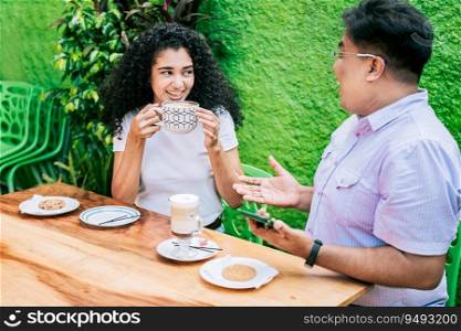 Smiling friends talking and enjoying coffee at a table. Concept of friends enjoying a good coffee. Two happy friends having a coffee and talking