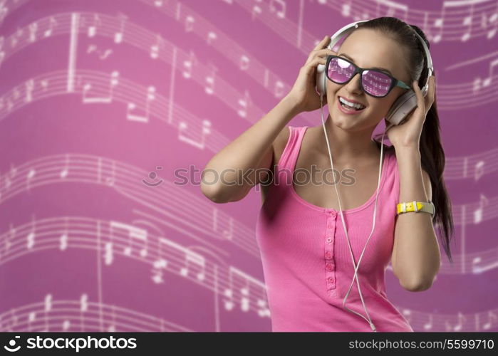 smiling funny girl listening music with headphones and posing with pink singlet and long brown ponytail