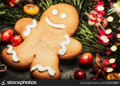 Smiling gingerbread men with fir branches, spices and festive bokeh lighting, close up