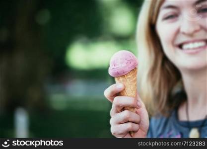 Smiling girl enjoys her strawberry ice cream during a summer day